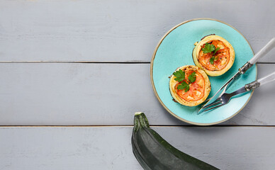 Top view of delectable baked zucchini, topped with cheese and tomatoes, presented on a ceramic...