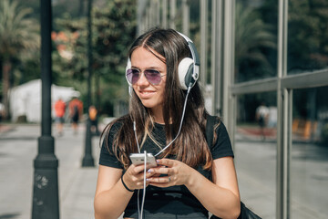 teen girl with headphones and phone walking down the street