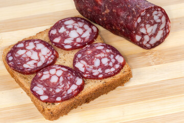 Open sandwich with dry-cured sausage slices against sausage piece