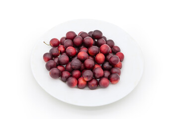 Red cherry plums on dish on a white background