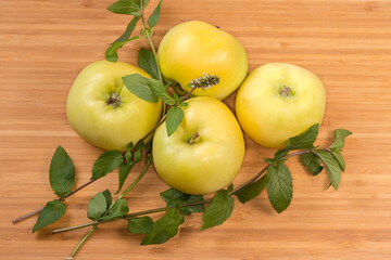 Yellow apples and stems of fresh mint on wooden surface