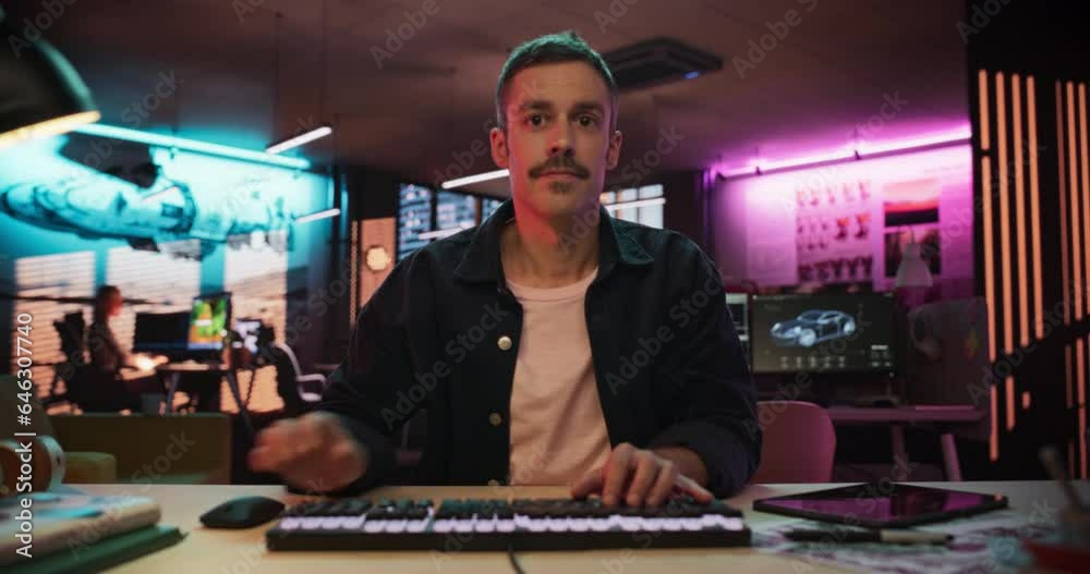 Poster Zoom Out Portrait of a Young Man Typing on Keyboard and Working on Desktop Computer in a Creative Office with Neon Lights. Male Software Developer Writing Code. Point of View of Screen Monitor