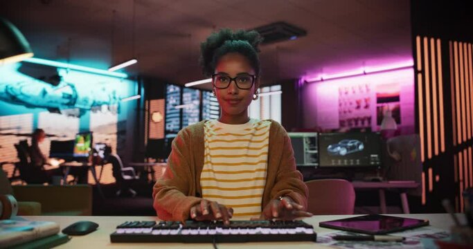 African American Female Smiling While Checking Data Using Desktop Computer. Portrait of a Happy Successful Black Businesswoman in Creative Agency in the Evening. Zoom Out POV of Screen Monitor