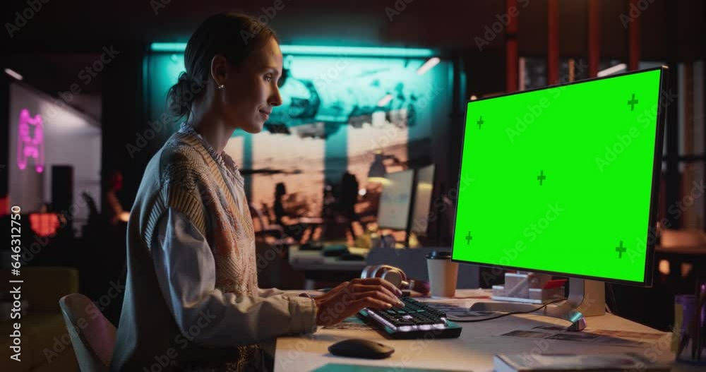 Poster zoom in portrait of young woman sitting at her desk using desktop computer with mock-up green screen