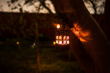 Beautiful colorful illuminated lamp in the garden in misty night. Retro style lantern at night outdoor.