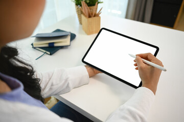 Over shoulder view of young woman using stylus pen writing on digital tablet