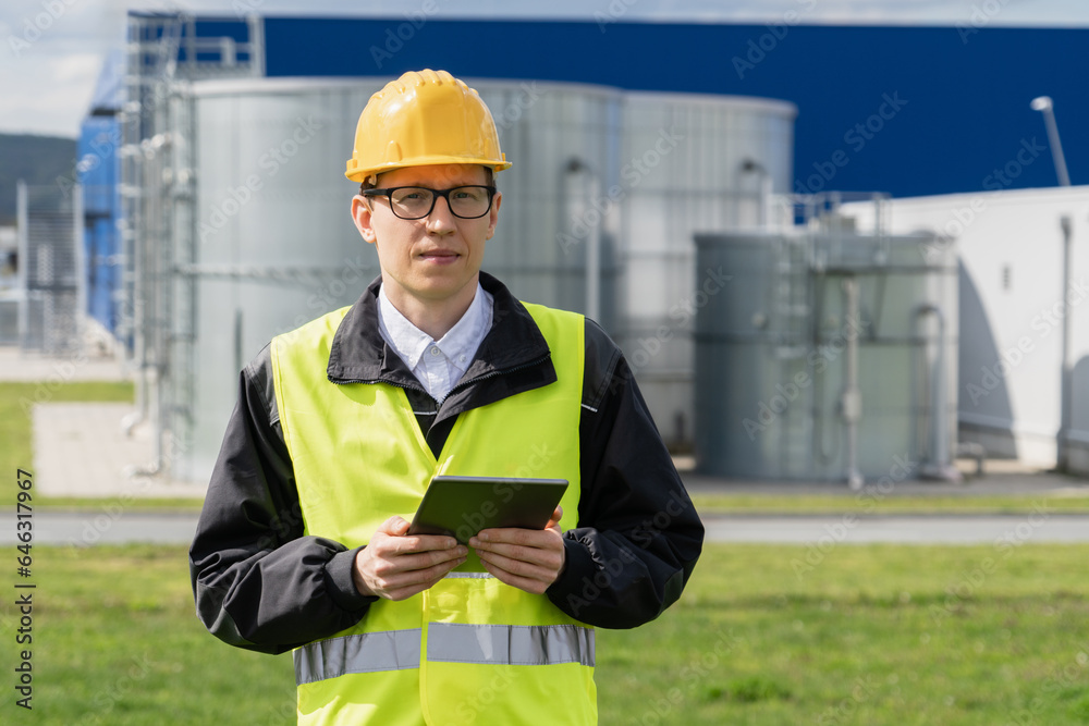 Poster Engineer with digital tablet on a background of gas tanks.