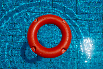 Konzept Sicherheit im Schwimmbad mit einem orangenfarbenen Rettungsring im Pool - obrazy, fototapety, plakaty