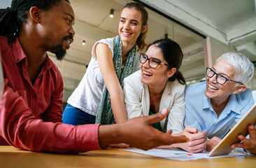 Fototapeta premium Smiling diverse colleagues gather in boardroom brainstorm discuss financial statistics together