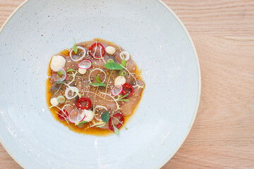 Top view of ceviche on a white plate on a wooden table in restaurant