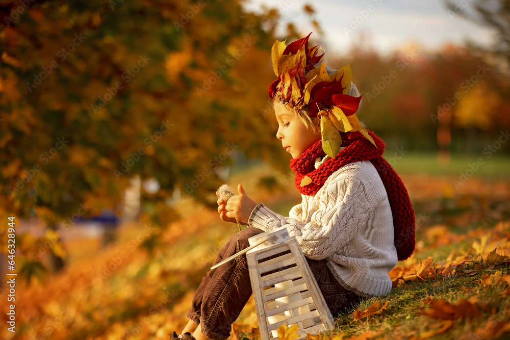 Poster Adorable little child, blond boy with crown from leaves in park on autumn day.