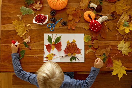 Child, Applying Leaves Using Glue, Scissors, And Paint, While Doing Arts And Crafts At Home