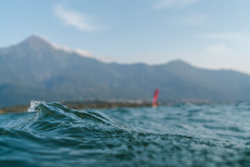 Abstract Water Surface Lake Wave windy day.Texture of dark blue water during sunset. Water surface in focus. Selective focus. Sunset Italy Lake Como windsurfer blurry in the background.