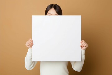 白いボードを体の前に掲げる日本人の若い女性（メッセージ・白い紙・クリップボード）
