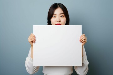 白いボードを体の前に掲げる日本人の若い女性（メッセージ・白い紙・クリップボード）