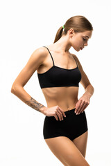 Fototapeta premium Beautiful sporty woman in black bikini posing on grey background. Beauty and body care concept