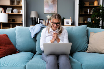 Young successful businesswoman working on laptop computer from home office. Business female finishing her work while sitting on sofa at her apartment.
