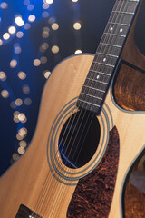 Obraz premium Close-up, acoustic guitar on a dark background with bokeh lights.