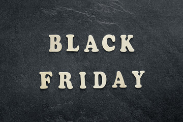 Wooden text Black friday on black textured background, top view.