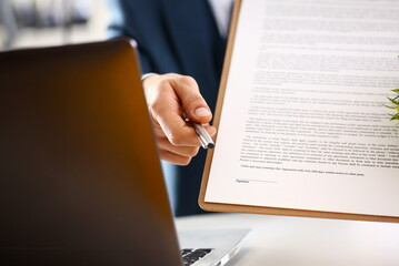 Male arm in suit offer contract form on clipboard pad and silver pen to sign closeup. Strike a...