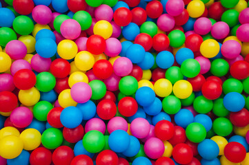 Top view of many multicolored plastic balls in a ball pool at a children's indoor playground....
