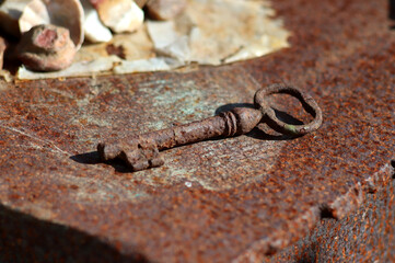 Rusty metal rustic old key on an iron surface - close-up, horizontal photo.