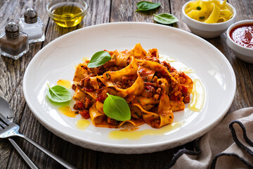 Tagliatelle con ragù alla bolognese - pasta with minced meat and tomato sauce on wooden table