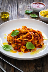 Tagliatelle con ragù alla bolognese - pasta with minced meat and tomato sauce on wooden table