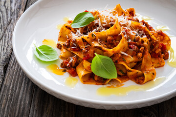 Tagliatelle con ragù alla bolognese - pasta with minced meat and tomato sauce on wooden table