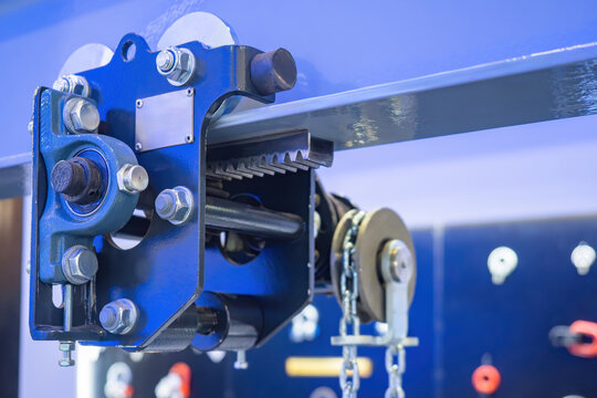 Suspended rail trolley. Mechanism for moving goods. Cargo trolley is suspended on metal beam. Industrial cargo equipment. Mechanism for moving weights around workshop. Blue hanging rail trolley
