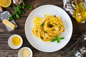 Linguine al limone - pasta with lemon and parmesan on wooden background

