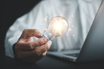 Inspiration and innovation, Businessman holds a creative light bulb, representing a new idea. Depicts the concept of brainstorming, solution, and successful profit in global business.