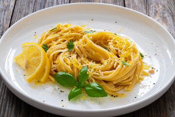 Linguine al limone - pasta with lemon and parmesan on wooden background
