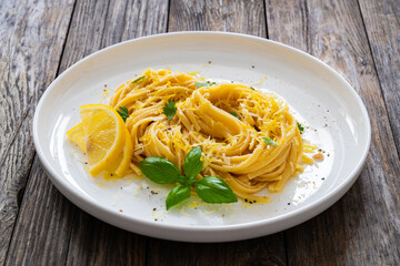 Linguine al limone - pasta with lemon and parmesan on wooden background
