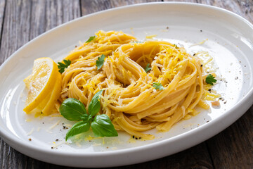 Linguine al limone - pasta with lemon and parmesan on wooden background
