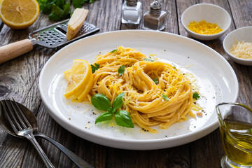 Linguine al limone - pasta with lemon and parmesan on wooden background

