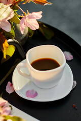 Cup of coffee flowers and notebook on the small black table