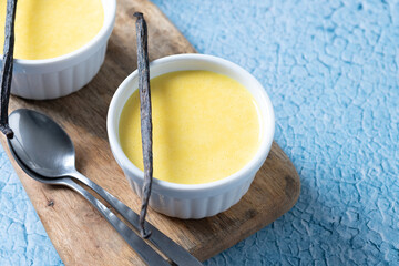Homemade vanilla custard on blue background. Copy space