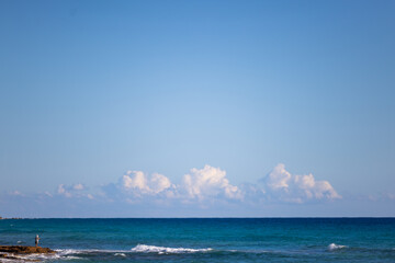 Horizon of the Mediterranean Sea. Old woman fishing on the edge.