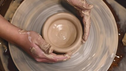 Potter girl works on potter's wheel, making ceramic pot out of clay in pottery workshop. Art and hobby concept. slow motion