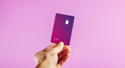 Electronic banking with a contactless credit card: Woman's hand holding a purple bank card