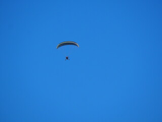 vista frontal de  parapente con vela fija color blanco y negro y motor de hélice volando bajo el cielo azul sobre las montañas del montsec aragones, huesca, españa, europa