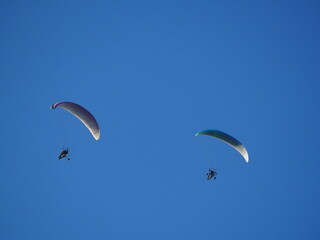 dos parapentes sobrevolando las murallas chinas de finestres bajo un cielo azul radiante, vela fija de color blanco y negro, motor de hélice y piloto, huesca, aragón, españa, europa 