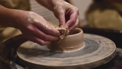 Potter girl works on potter's wheel, making ceramic pot out of clay in pottery workshop. Art and hobby concept. slow motion