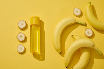 Transparent bottle decorated with several fresh banana slices. Banana (Musaceae) can help with aging as well. Organic skin care concept of banana extract