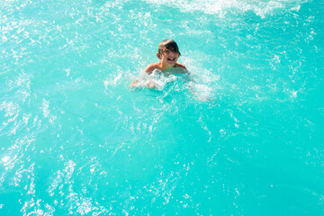 happy boy swim in the pool. joyful wet child swims in the water.	