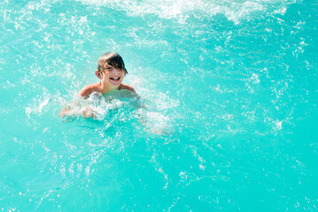happy boy swim in the pool. joyful wet child swims in the water.