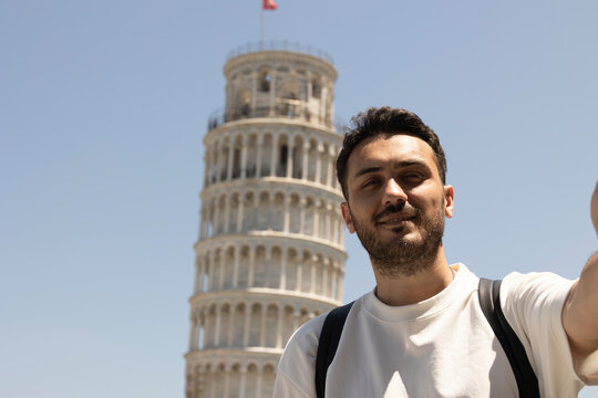 Young tourist man taking selfie with pisa tower in Italy. 