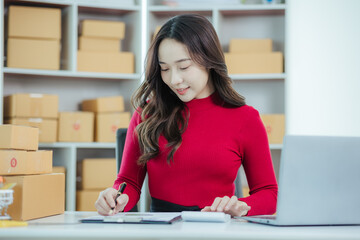 Startup small business entrepreneur or freelance Asian woman using a laptop with box, Young success Asian woman with her hand lift up, online marketing packaging box and delivery, SME concept.