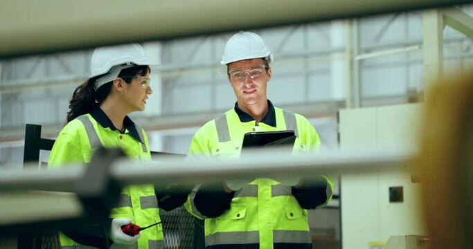 Two engineer checking machine in factory together. They Work at the Heavy Industry Manufacturing Facility.